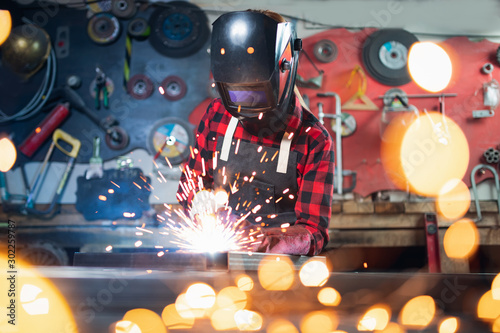 Portrait industrial worker craft labourer factory welding steel structure with spark