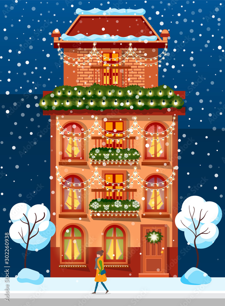Urban brick building, housing for people. Facade, front exterior on Christmas holiday, snowy trees near and Xmas decor. Festive decoration like garlands from fir branches and light lamps