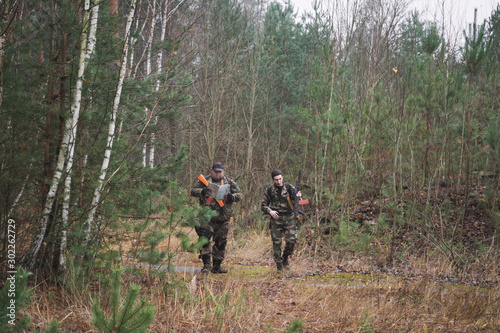 Two soldiers of a special unit are walking n autumn forest