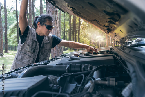 Asian man Opening the bonnet of his pickup truck to check the condition of the engine failure, to be ready for travel, to transportation concept.