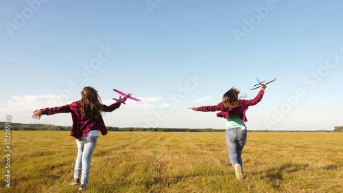 children play toy airplane. teenagers want to become pilot and astronaut. Happy girls run with toy plane at sunset on field. concept of happy childhood. Girls dream of flying and becoming a pilot.