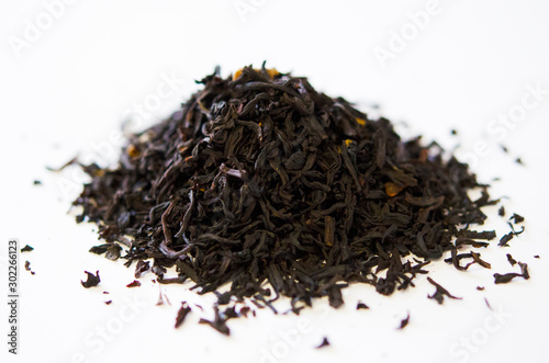 Black tea with additives close-up on a white background. A handful of tea for brew.