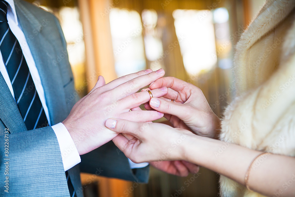 Obraz premium groom wears a ring on finger of his beloved