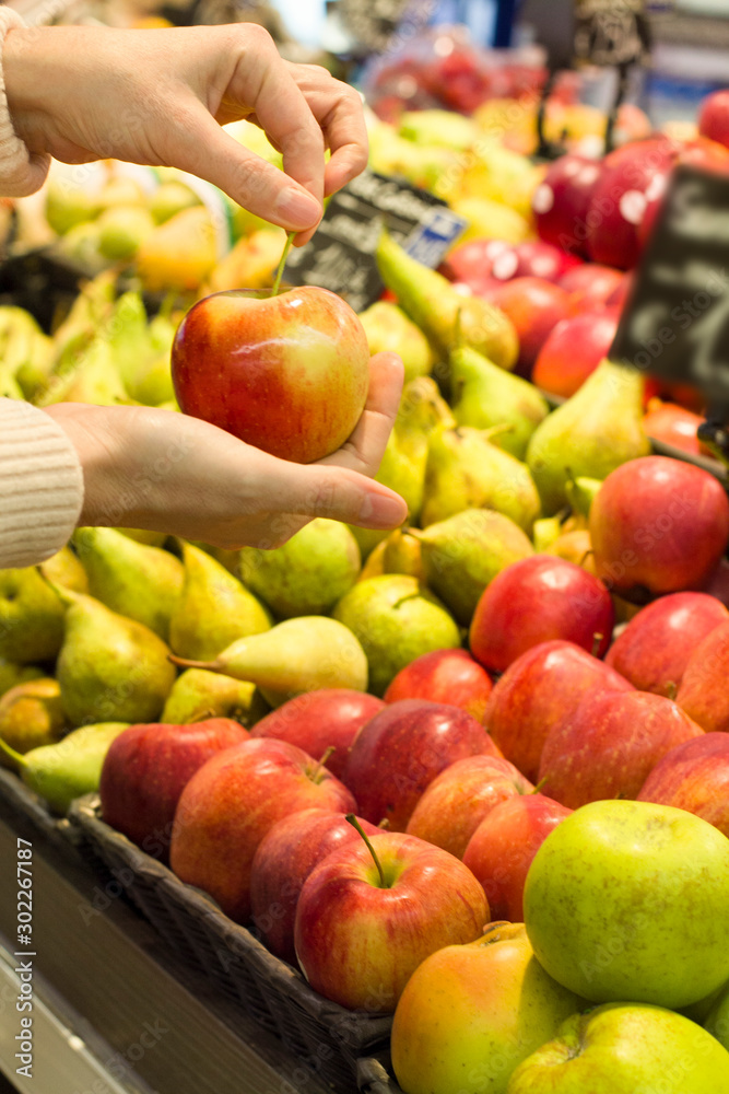 Female hand choosing apple in the store. Concept of healthy food, bio, vegetarian, diet.