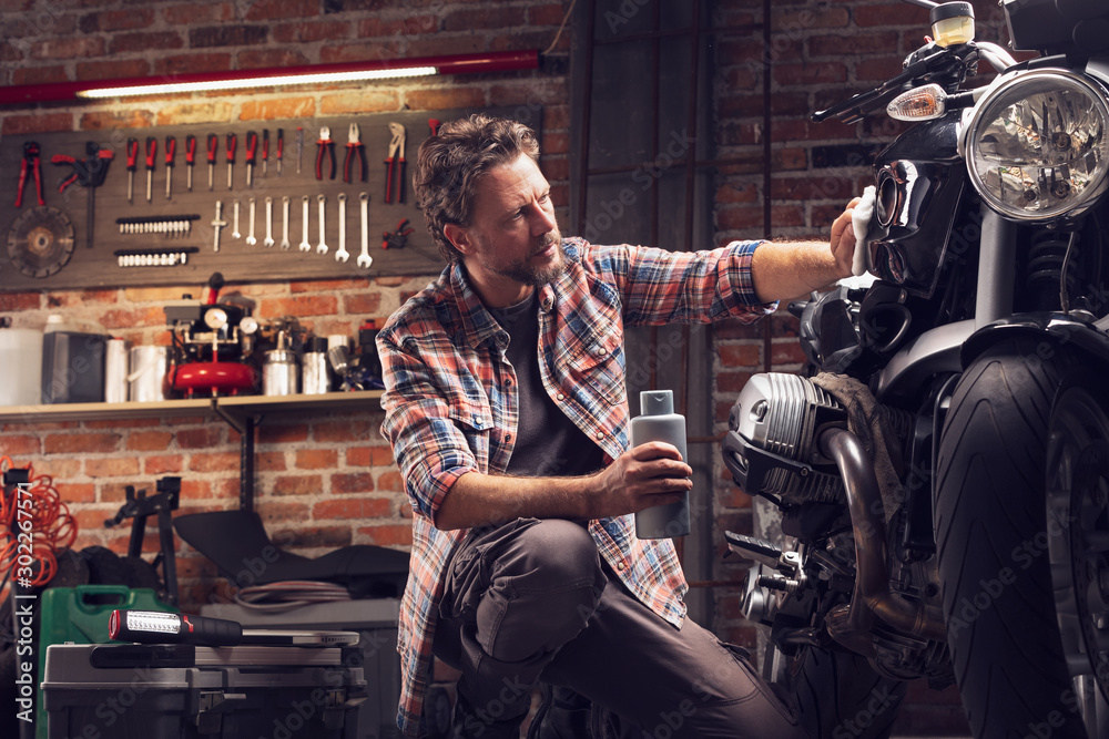Man polish motorcycle in garage - obrazy, fototapety, plakaty 