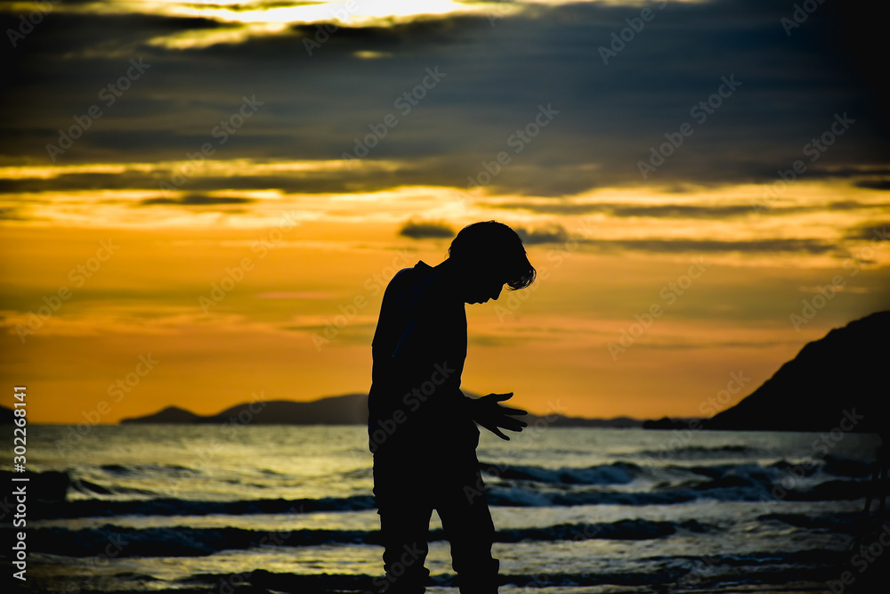 Man stand alone on beach at twilight