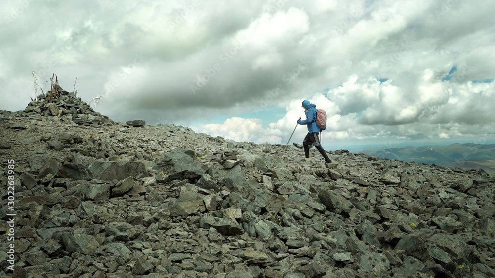 Ultra trail runner climbing a stone trail to the mountain top. A challenge to human strength and ability.
