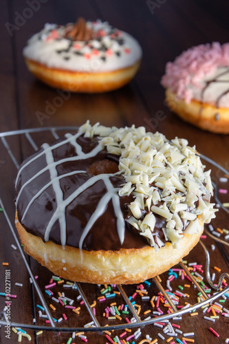 delicious donuts with topping on wooden background