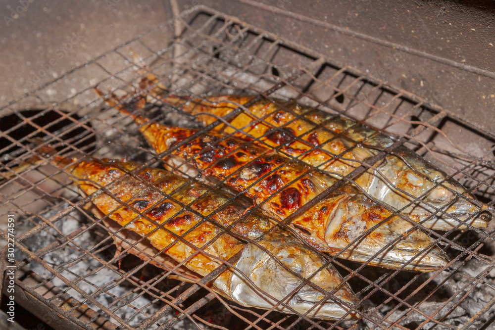 Grilled smoked Golden mackerel fish outside late at night