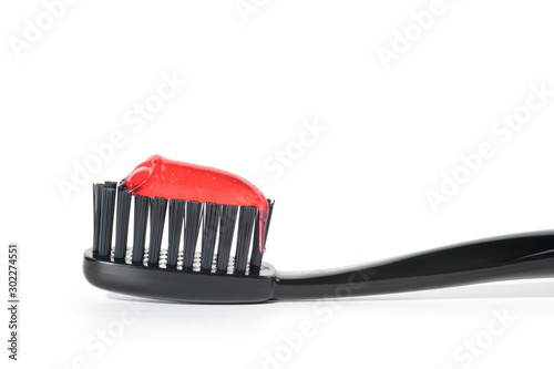 Black toothbrush with red toothpaste isolated on white