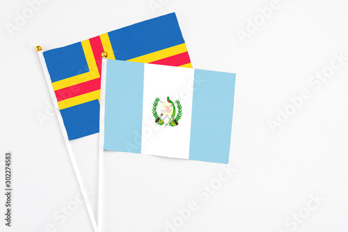 Guatemala and Aland Islands stick flags on white background. High quality fabric, miniature national flag. Peaceful global concept.White floor for copy space.