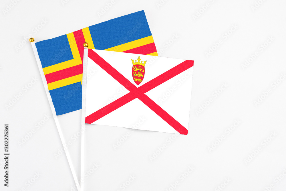 Jersey and Aland Islands stick flags on white background. High quality fabric, miniature national flag. Peaceful global concept.White floor for copy space. Jersey and Aland Islands stick flags on white background. High quality fabric, miniature national flag. Peaceful global concept.White floor for copy space.