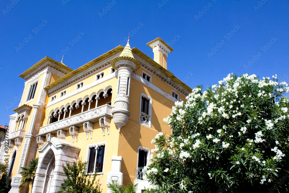 Beautiful view of yellow house and white flowers  on a sunny day. Traditional architecture. Cascais. Portugal.