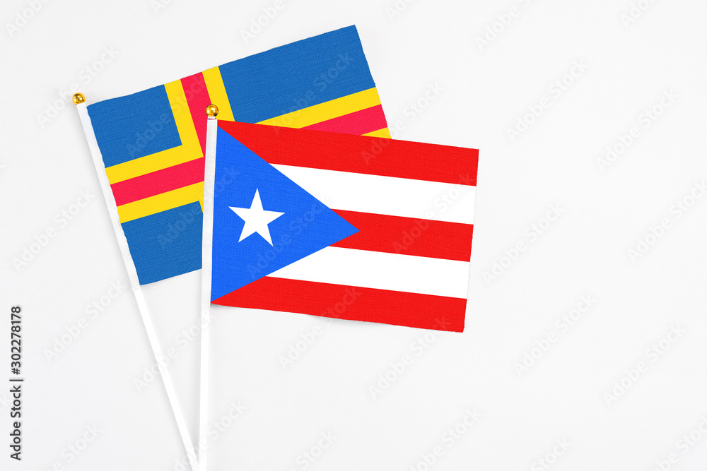 Puerto Rico and Aland Islands stick flags on white background. High quality fabric, miniature national flag. Peaceful global concept.White floor for copy space.