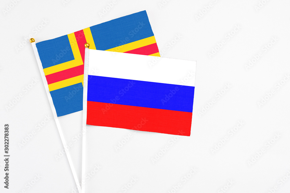 Russia and Aland Islands stick flags on white background. High quality fabric, miniature national flag. Peaceful global concept.White floor for copy space. Russia and Aland Islands stick flags on white background. High quality fabric, miniature national flag. Peaceful global concept.White floor for copy space.