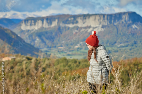 a girl alone in the mountain, wears a hat and is warm, it's autumn and it's cold