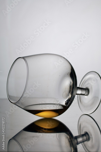 Short-stemmed wine glass. Lies on its side, photographed in the light. It has a small amount of alcohol.