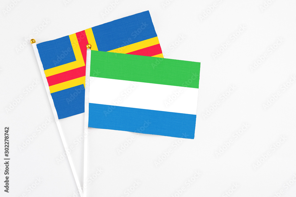 Sierra Leone and Aland Islands stick flags on white background. High quality fabric, miniature national flag. Peaceful global concept.White floor for copy space. Sierra Leone and Aland Islands stick flags on white background. High quality fabric, miniature national flag. Peaceful global concept.White floor for copy space.