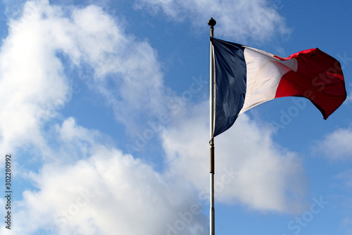 the flag of France is flying in the wind against the blue sky and clouds