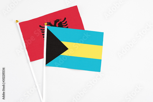 Bahamas and Albania stick flags on white background. High quality fabric, miniature national flag. Peaceful global concept.White floor for copy space.