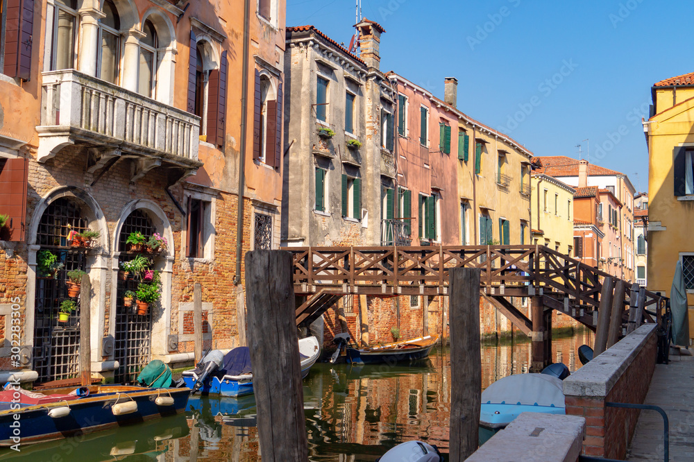 Venice, Italy. Venice, Italy. Boats moored in narrow canal under wooden bridge