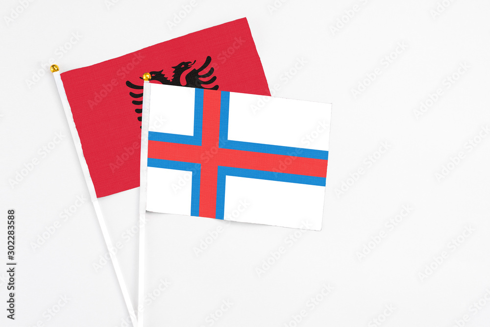 Faroe Islands and Albania stick flags on white background. High quality fabric, miniature national flag. Peaceful global concept.White floor for copy space.