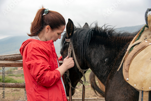 A woman gently stroking the horse's muzzle in the background of a misty mountain landscape.