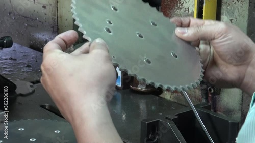 A factory operator is supervising with his hands the sprocket that they have just drilled. Manufacture of sprockets. photo