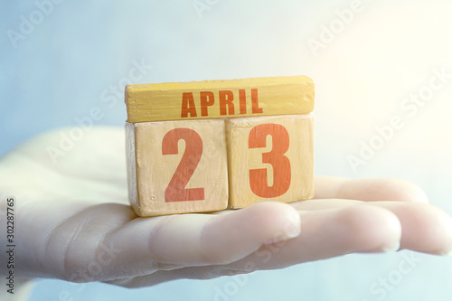 april 23rd. Day 23 of month,Handmade wood cube with date month and day on female palm spring month, day of the year concept