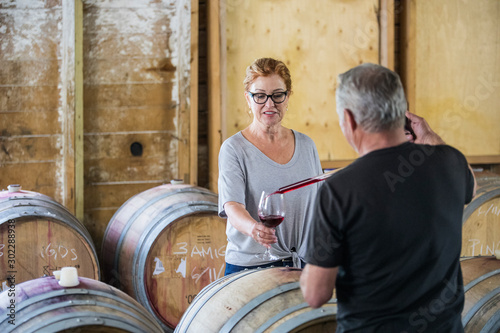 winemaker uses pipette to pour sample glass of wine to investor. photo