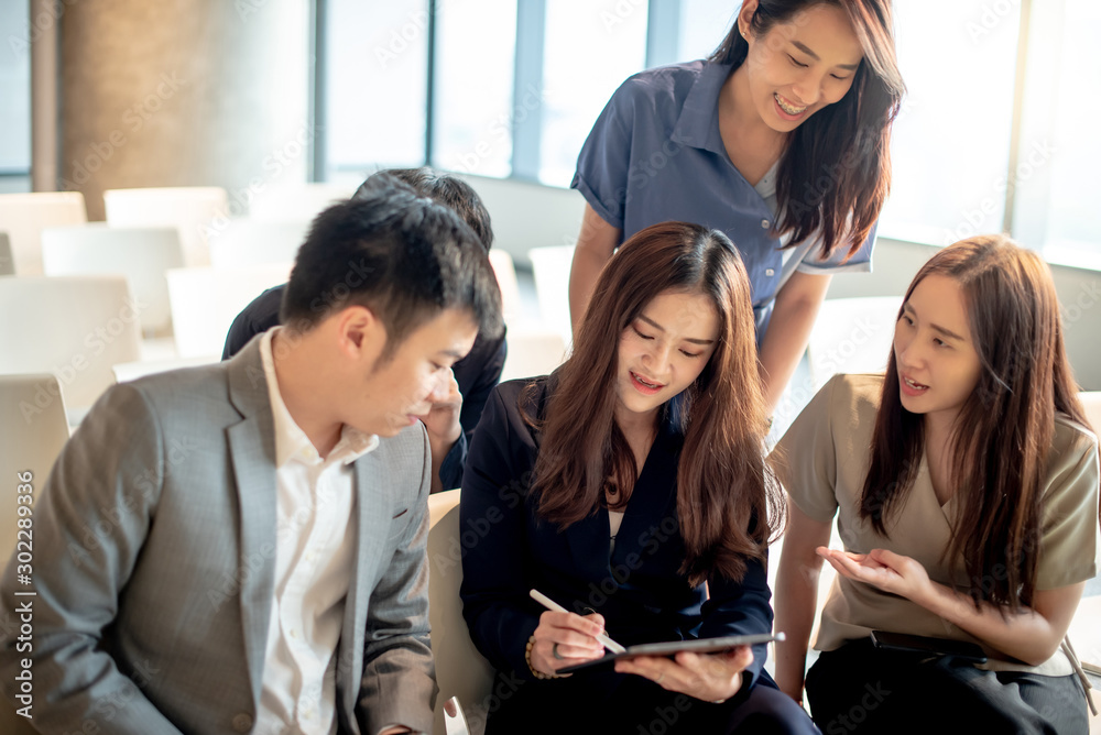 Business meeting and teamwork concept. Group of Asian colleagues discussing about project data report using digital tablet in conference room. Coworkers team sharing productive ideas in modern office.