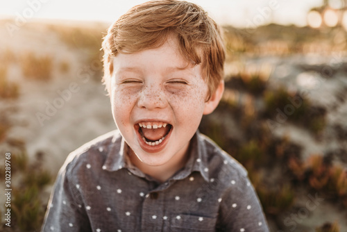 Front view of young kindergarten age boy laughing during beach sunset photo