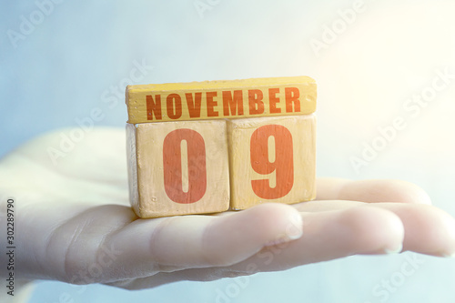 november 9th. Day 9 of month,Handmade wood cube with date month and day on female palm autumn month, day of the year concept