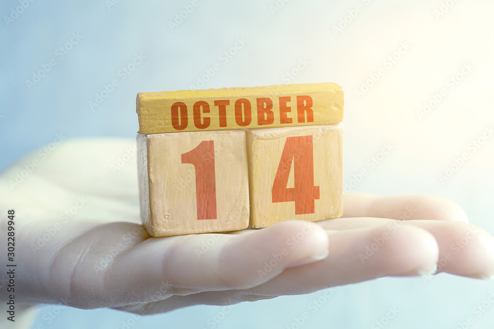 october 14th. Day 14 of month,Handmade wood cube with date month and day on female palm autumn month, day of the year concept october 14th. Day 14 of month,Handmade wood cube with date month and day on female palm autumn month, day of the year concept