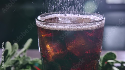 Cola with Ice and bubbles in glass. Cocktail with whiskey and rum. Ice cold drink. Drinking carbonated Soda. Beverage for thirst. Close-up. Glassful with ice. Slow motion.