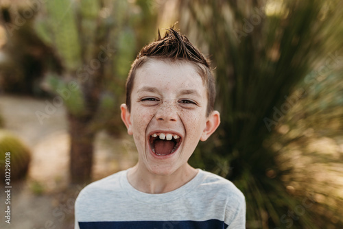 Close up portrait of cute young boy with freckles laughing outdoors
