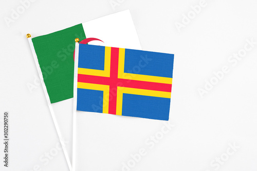 Aland Islands and Algeria stick flags on white background. High quality fabric, miniature national flag. Peaceful global concept.White floor for copy space.
