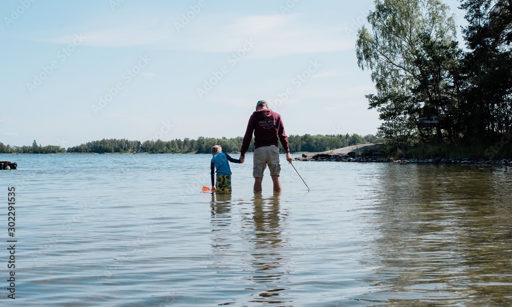 father holding his son's hand whilst fishing with a net in the sea father holding his son's hand whilst fishing with a net in the sea
