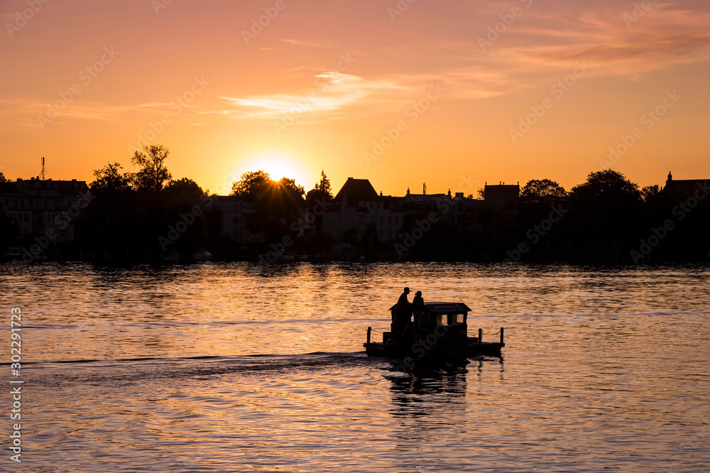View on a very romantic part of the city Potsdam, small boat swimming on the Havel, towards the sunset