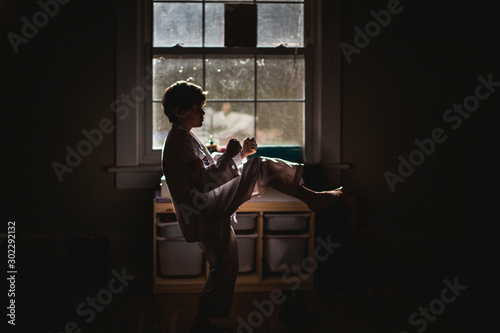 Canvas Print A small boy in uniform practices Taekwondo in early morning light
