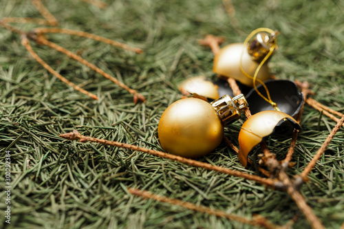 Broken golden Christmas balls on fallen dry Christmas tree needles with branches.