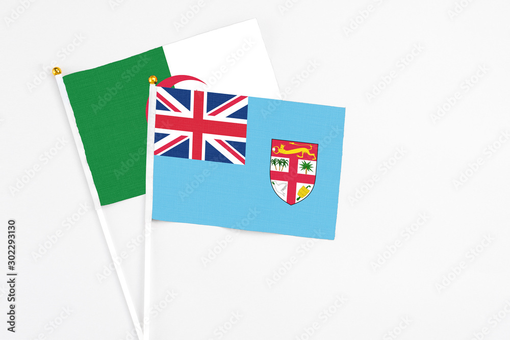 Fototapeta premium Fiji and Algeria stick flags on white background. High quality fabric, miniature national flag. Peaceful global concept.White floor for copy space.