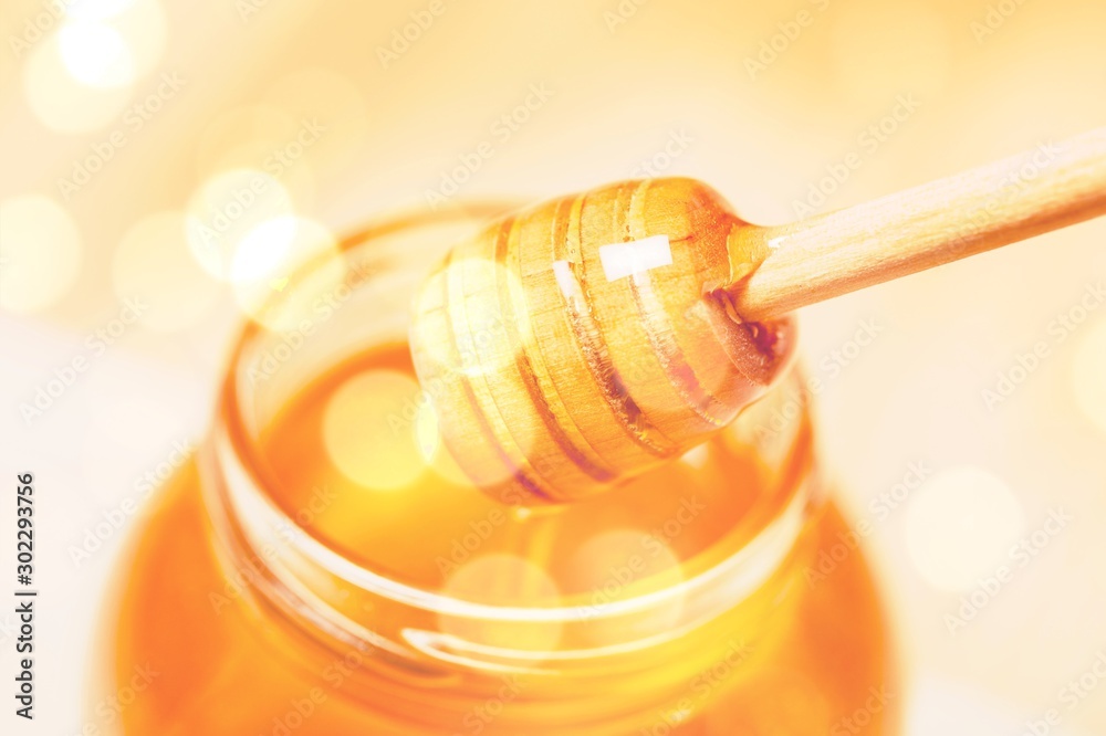 Honey with spoon in glass bowl on glossy background Honey with spoon in glass bowl on glossy background