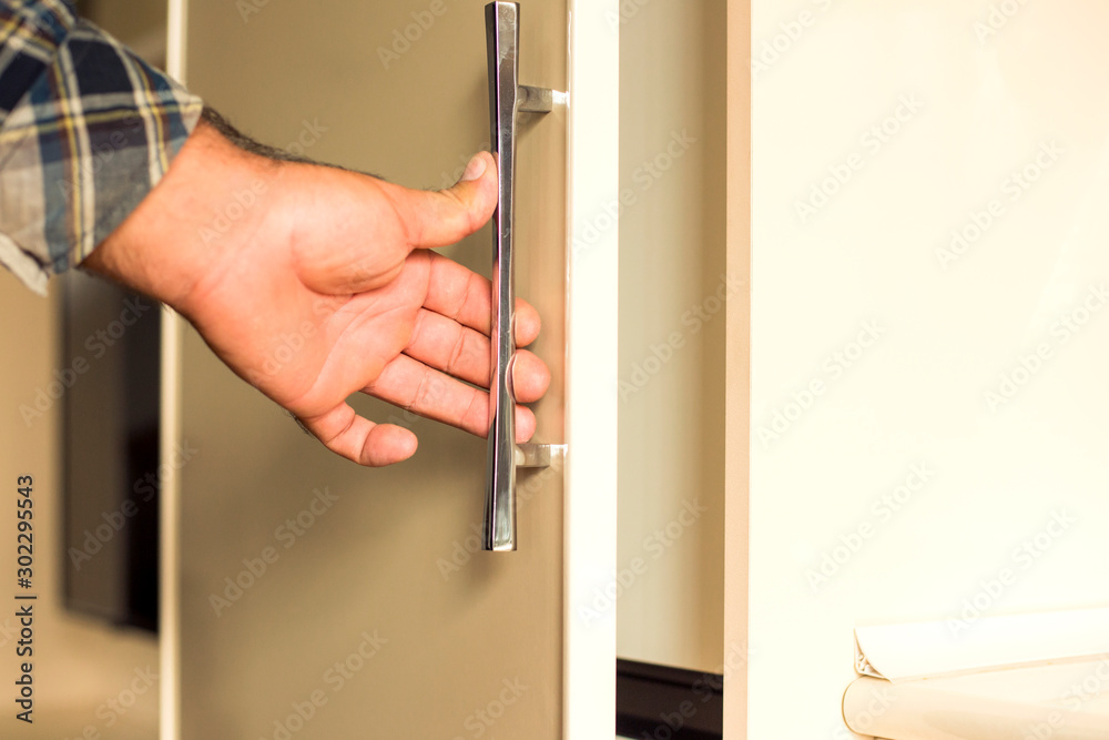 Man opens white wardrobe door
