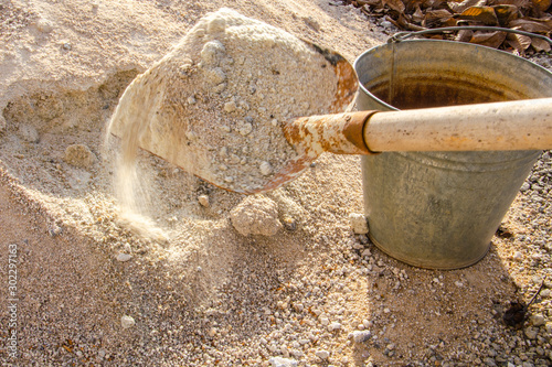 Loading sand with a shovel into a bucket