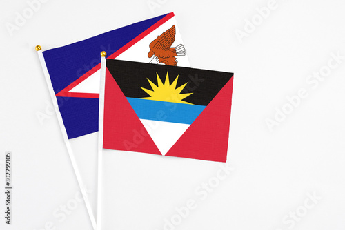Antigua and Barbuda and American Samoa stick flags on white background. High quality fabric  miniature national flag. Peaceful global concept.White floor for copy space.