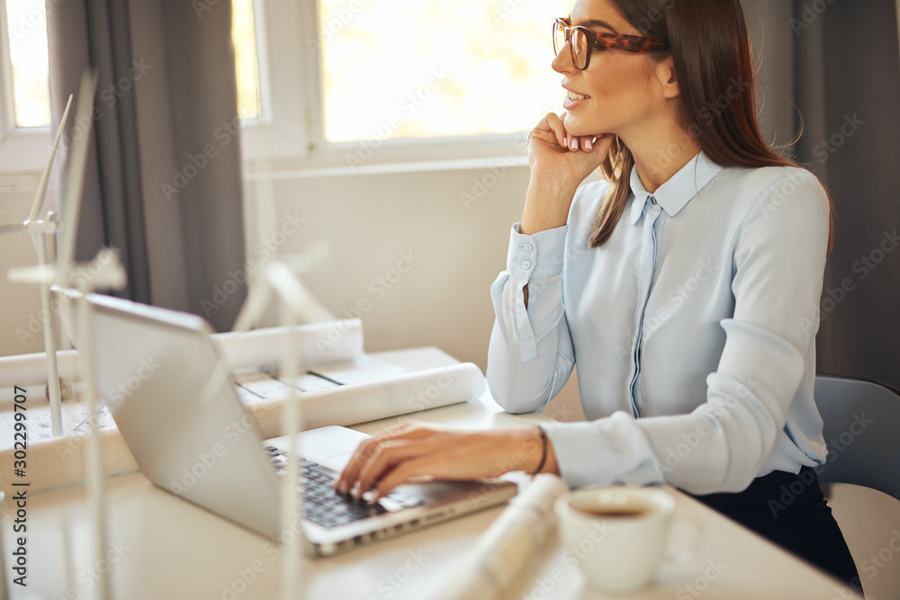 Focused beautiful caucasian businesswoman in formal wear sitting in office and using laptop. Sustainable development concept. Focused beautiful caucasian businesswoman in formal wear sitting in office and using laptop. Sustainable development concept.
