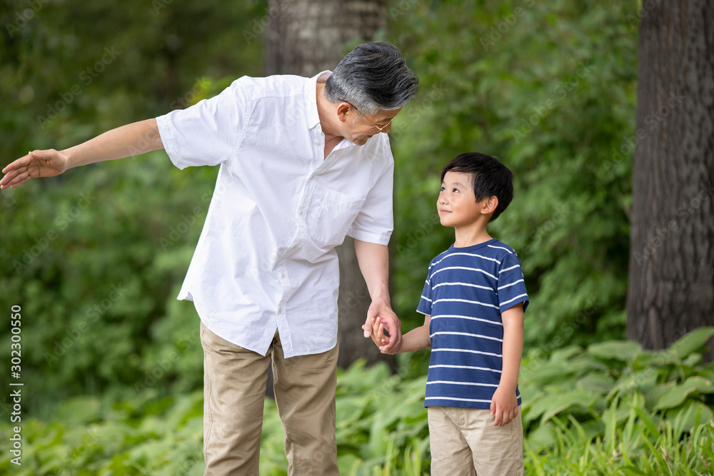 Happy Chinese grandfather and grandson holding hands in park Happy Chinese grandfather and grandson holding hands in park