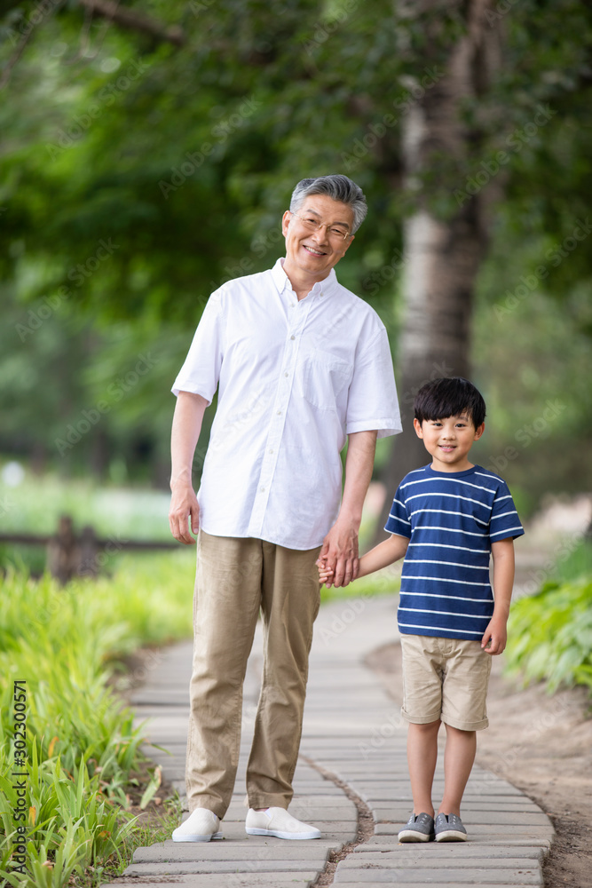 Happy Chinese grandfather and grandson holding hands in park Happy Chinese grandfather and grandson holding hands in park