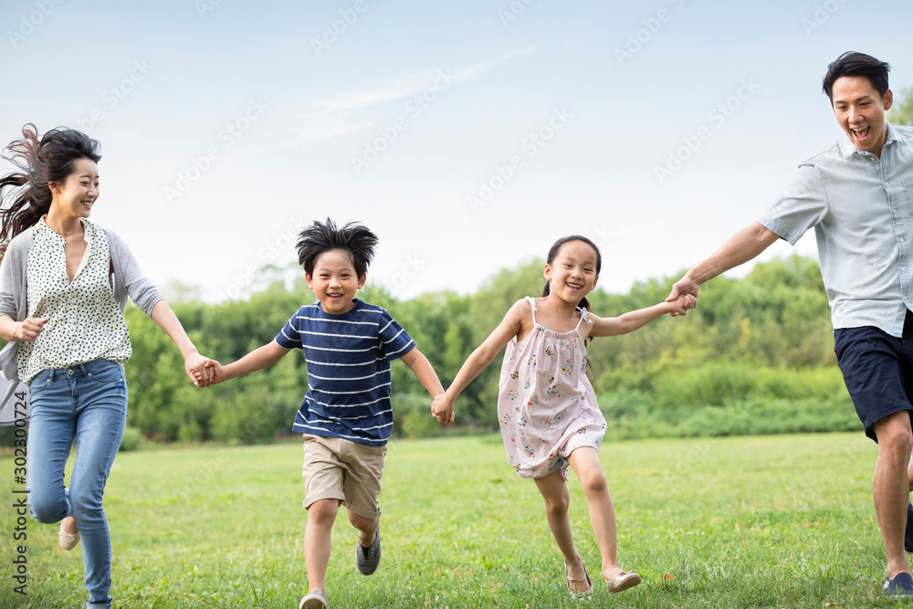 Happy young Chinese family running on grass Happy young Chinese family running on grass